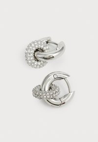 Pendientes de plata que presentan dos anillos entrelazados; uno es liso y brillante, mientras que el otro está adornado con pequeños cristales.