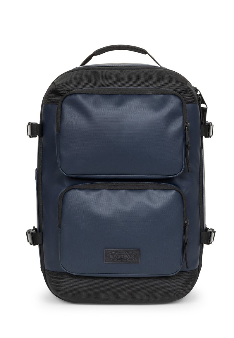 Zaino blu navy con texture liscia, dotato di due tasche anteriori con zip, dettagli neri e una maniglia superiore. Tessuto resistente e design minimalista.