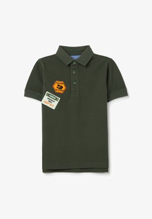 Polo de color verde oscuro hecho de tela texturizada; presenta un cuello, tres botones y dos parches coloridos con texto de advertencia.