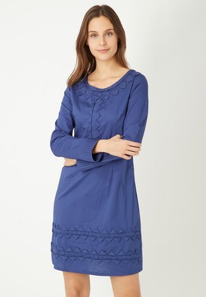 Vestido de algodón azul con mangas largas, escote redondo y detalles decorativos de ribete geométrico a lo largo del escote y el dobladillo. Textura suave.