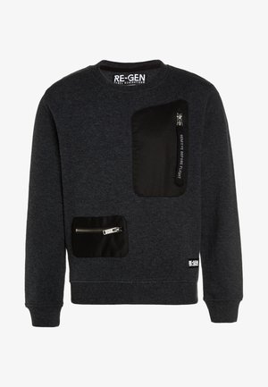 Sweatshirt gris foncé à col rond avec deux poches zippées noires, une grande sur la poitrine et une plus petite près de la taille, avec une étiquette "REMOVE BEFORE FLIGHT".