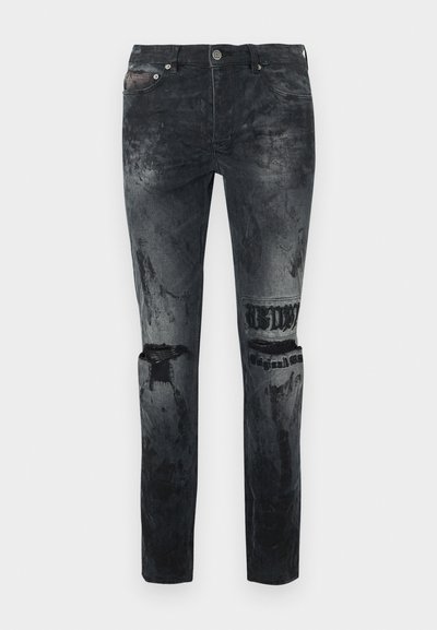 Mustad teksapüksid kulunud viimistlusega. Omavad nähtavaid rebendiga aktsente, eesmist nööpide sulgemist ja keerukaid õmbluse detaile.