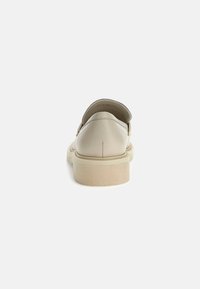 Beige leather slip-on shoes with a rounded toe, low platform sole, and minimal stitching details on the back.