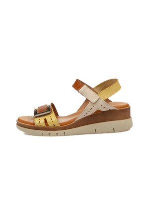 Sandalias de cuña con una combinación de colores marrón, amarillo y crema, correa ajustable, acento metálico y detalles perforados en la parte superior.