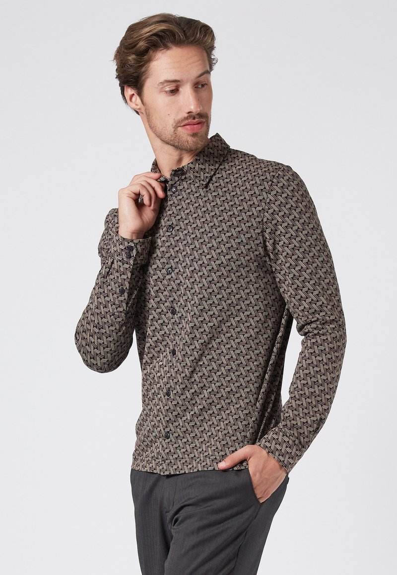 Camisa de manga larga con un patrón geométrico en zigzag, con botones oscuros y un cuello abotonado, fabricada con una suave mezcla de algodón.