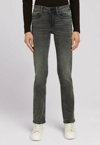 Smal passform jeans i blekt mörkgrå denim. Har klassisk femfickestil och knappgylf. Bärs med vita sneakers.