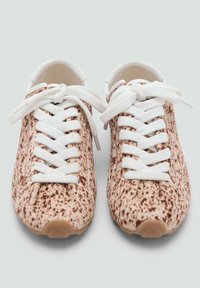 Zapatillas con un material beige moteado, cordones blancos, punta redondeada y superficie texturizada, presentando un diseño de perfil bajo.