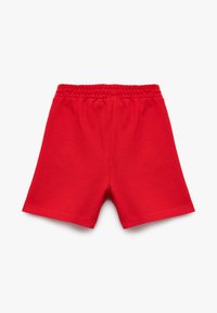 Röda kortbyxor i bomull med elastisk midja. Slät textur med en enkel design och inga ytterligare mönster eller dekorationer.