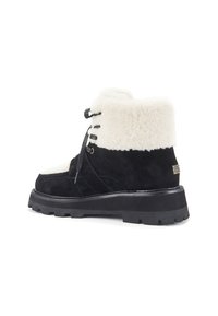 Černé a bílé semišové kotníkové boty s nadýchaným bílým límcem, černými šněrovadly, zlatými detaily a robustní černou podrážkou.