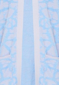 Jasnoniebieski kardigan z teksturowanym wzorem, wykonany z miękkiego, puszystego materiału i z białymi pasami akcentującymi. Posiada przednie kieszenie.