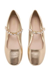 Guld läder Mary Jane-skor med platt sula, med en rem över fotryggen dekorerad med pärlor och rhinestone. Rund tå-design.
