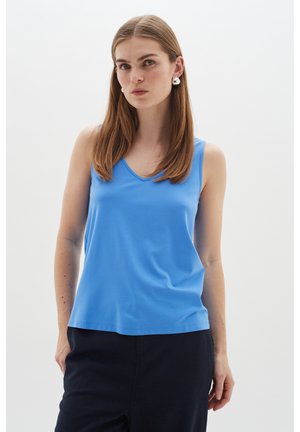 Top albastru fără mâneci dintr-un material fin, cu un decolteu în V, combinat cu pantaloni închiși. Modelul afișează o expresie neutră și accesorii simple.