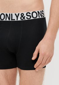 Czarne bawełniane bokserki z białym elastycznym paskiem w talii, na którym czarnym nadrukiem znajduje się napis "ONLY & SONS". Miękka tekstura, dopasowany krój.
