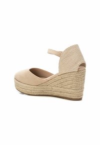 Zapato de cuña de ante beige con una correa de tobillo de patrón y una plantilla de yute trenzado. Punta redondeada y parte trasera texturizada para un detalle adicional.