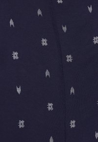 Tissu bleu marine avec un motif de petites formes géométriques blanches et lignes, ayant une texture lisse et un léger éclat.