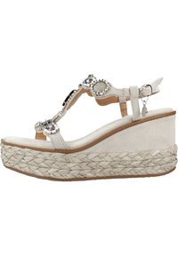 Sandalia de cuña beige con plataforma de yute trenzado, parte superior de ante, tiras adornadas con piedras y acentos de metal. Diseño minimalista.