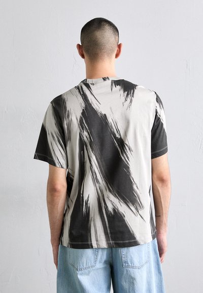 Rövid ujjú póló, szürke fekete ecsetvonás mintával, pamut anyagból, laza fazonnal, kerek nyakkal, látható varrási részletekkel.