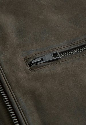 Tummanoliivinvihreä nahkakangas, jossa on teksturoitu pinta ja vetoketjullinen tasku mustalla metallivarustuksella.