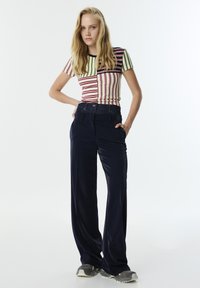 Gestreepte top met korte mouwen in crème, rood en groen, gecombineerd met een wijde marineblauwe broek. Gestructureerde stof, casual fit, met zijzakken.