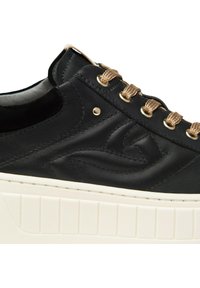 Sneaker in pelle nera con hardware color oro e lacci beige. Presenta un design laterale testurizzato e una spessa suola in gomma bianca con scanalature.