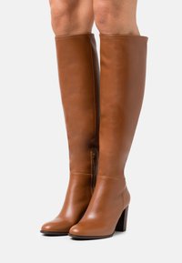 Knee-high brown leather boots with a smooth texture, featuring a side zipper and a block heel. Simple design with minimal accents.