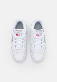 Baskets blanches avec tige en cuir, dotées d'une languette rembourrée, d'une boîte à orteils perforée et d'un logo Reebok agrémenté d'un accent rouge.