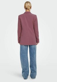 Lila maßgeschneiderte Blazer, lange Ärmel, glattes Material, Ein-Knopf-Verschluss, kombiniert mit weit geschnittenen blauen Jeans, Rückansicht.