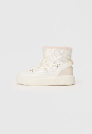 Botas de tobillo blancas acolchadas con un collar de piel sintética rosa, parte frontal con cordones y suela gruesa texturizada. Presentan un acento marrón en el costado.