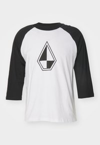 Hvid baseball t-shirt med sorte raglanærmer. Har et fremtrædende diamantformet sort og hvidt grafisk design på forsiden. Blød stofstruktur.