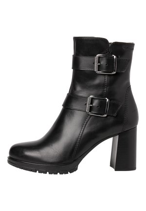Bottine en cuir noir avec un bout rond, deux sangles latérales avec des boucles en argent, et un talon bloc texturé. Semelle en caoutchouc pour une bonne traction.