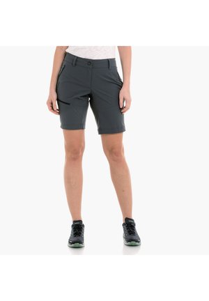 Pantalones cortos de senderismo grises hechos de tela ligera, con cierre de botón, dos bolsillos laterales y un ajuste relajado, combinados con zapatillas negras.