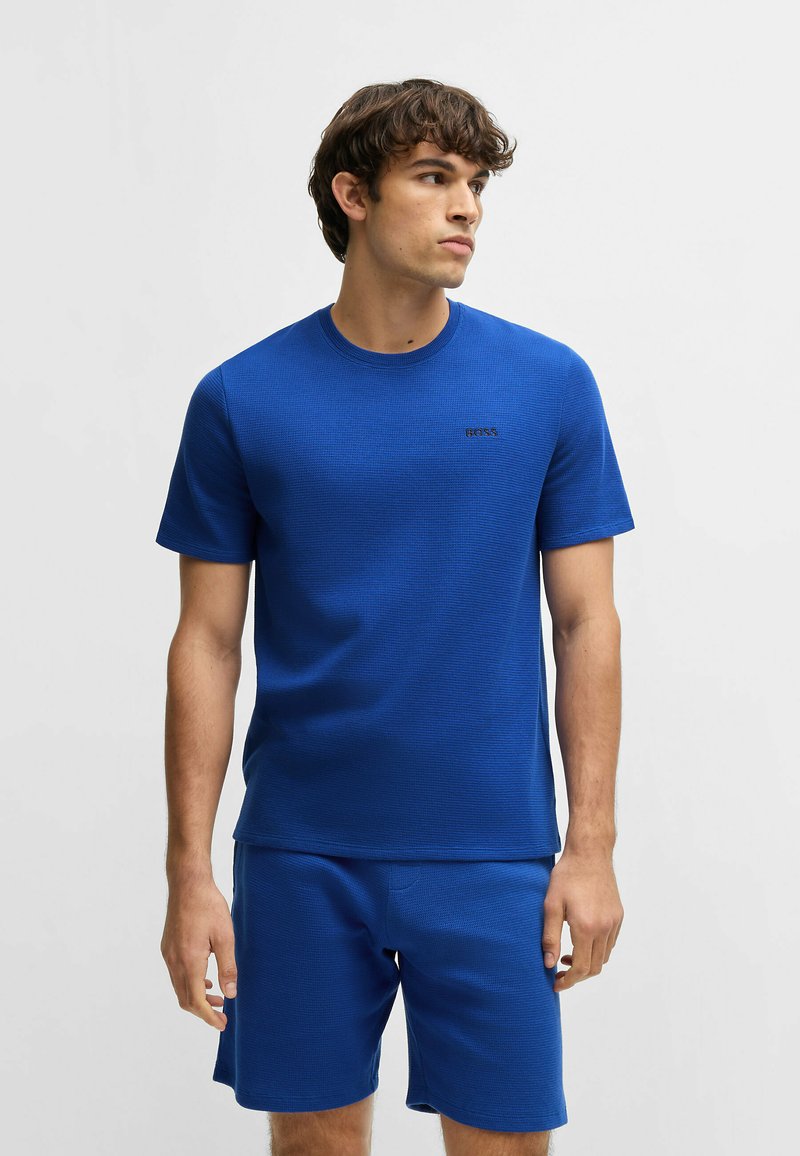 Blue athletic t-shirt with short sleeves, made of textured fabric, featuring a round neckline and a small black logo on the chest.