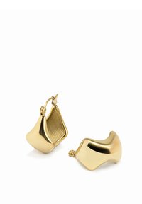 Guldiga hoopsörhängen med en slät, organisk form med varierande konturer och en inre textur. Designen är minimalistisk och modern.