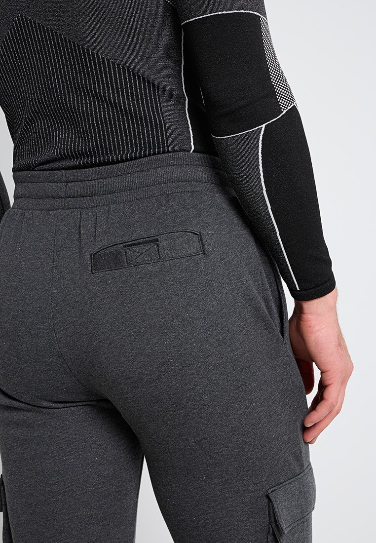 Dopasowana czarna bluzka z długim rękawem o teksturowanym prążkowanym wzorze oraz szare dresy z tylną kieszenią i elastycznym pasem.