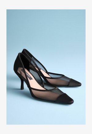 Fekete magassarkú cipők hálós panelek és hegyes orrok jellemzik, vékony sarokkal és sima selyem részletekkel.