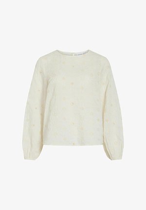 Blouse crème à manches longues avec broderie délicate en œillets floraux, col rond et poignets élastiqués, présentée sur fond blanc.