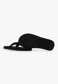 Infradito nere con una suola in gomma texturizzata e cinturini in tessuto intrecciato, caratterizzate da un design piatto e uno stile minimalista.
