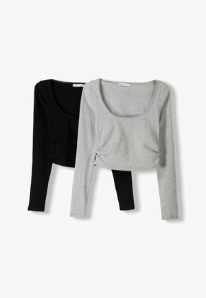 Musta ja harmaa lyhythihainen, lyhennetty paita. Pehmeä ribbikangas, avonainen kaula-aukko, tiukka malli sivuilla muotoiluperusyksityiskohdilla.