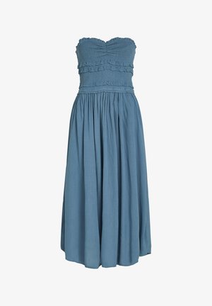 Olkaimeton pitkä mekko pehmeässä sinisessä kankaassa, jossa on rypytyksiä vartalolla ja röyhelökoristeita, sekä hulmuava hame, joka ulottuu nilkkoihin.