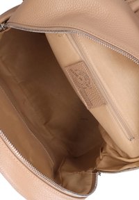 Beige leren handtas interieur met een gestructureerde afwerking, voorzien van een zijritszak en een gladde voering, met een eenvoudig ontwerp.