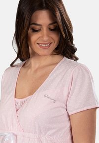 Maglietta da notte rosa a pois con maniche corte, scollatura a V e vita con cordoncino elasticizzato. Presenta un delicato ricamo sul petto.