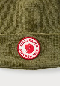 Gorro de malha verde-oliva com dobra, apresentando um logo redondo em vermelho e branco da Fjällräven Suécia 1960.