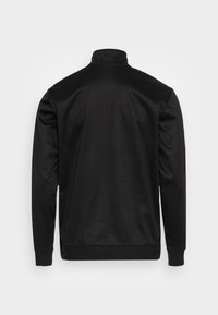 Czarna, długosleeve'owa bluzka z wysokim kołnierzem. Gładka tekstura, elastyczny materiał i dopasowany krój. Brak widocznych logo lub wzorów.