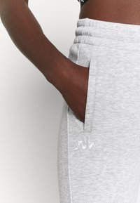Grijze joggingbroek met een zachte textuur, voorzien van een geborduurd logo aan de zijkant, zijzakken en een elastische tailleband voor een stevige pasvorm.