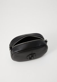 Borsa cosmetica nera in pelle, con superficie testurizzata, forma ovale, chiusura con zip superiore e logo in rilievo sul davanti.