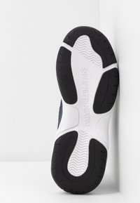 Calvin Klein Jeans sneakers med en texturerad marinblå ovandel, vit mellansula och svart gummisula med greppmönster och varumärkesdetaljer.