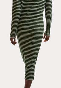Strickkleid mit enger Passform, ausgestattet mit grünen und weißen wellenförmigen Streifen. Lange Ärmel und knielange Länge mit geripptem Muster über die gesamte Fläche.