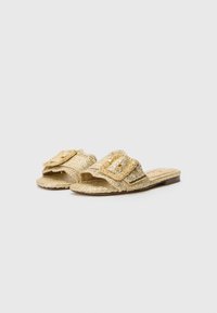Gold woven slide sandals with a textured finish, featuring a large decorative buckle and a flat sole. Detailed stitching along the edges.