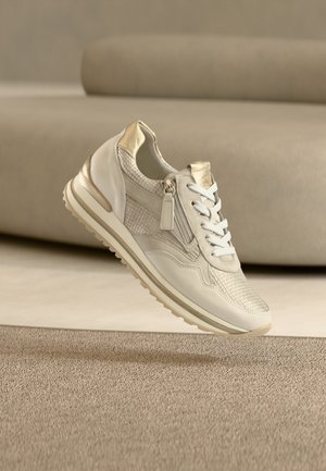 Hvid sneaker med metalliske accenter, detaljer i tekstureret mesh, snørelukning og en lynlås. Har en polstret sål og minimalistisk design.