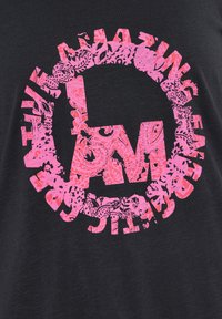 Černé tričko s velkým růžovým grafickým motivem se složitými květinovými vzory tvořícími písmena "L" a "M" uvnitř kruhového designu.